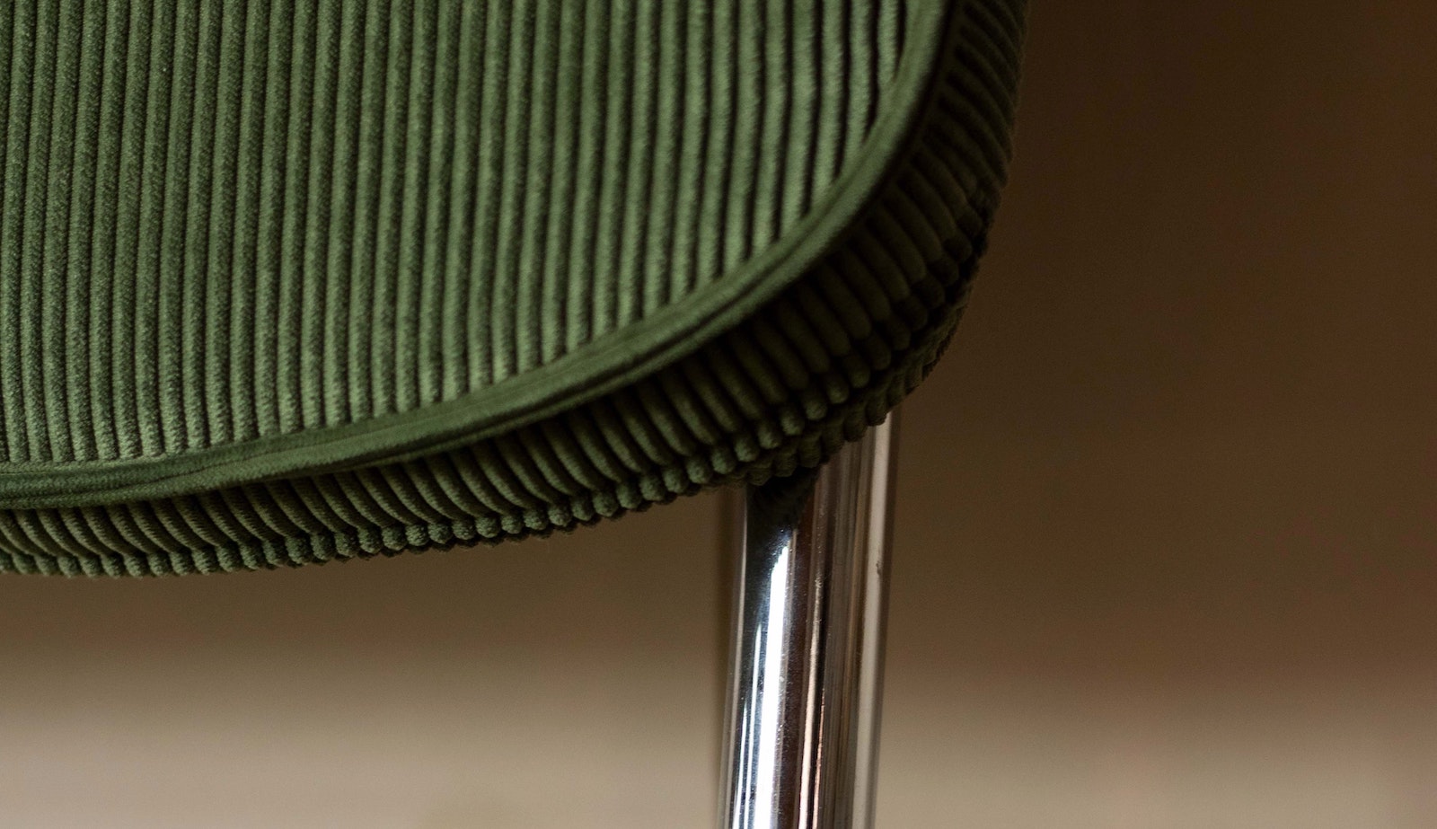 Close up of a green cord chair back with silver metal frame