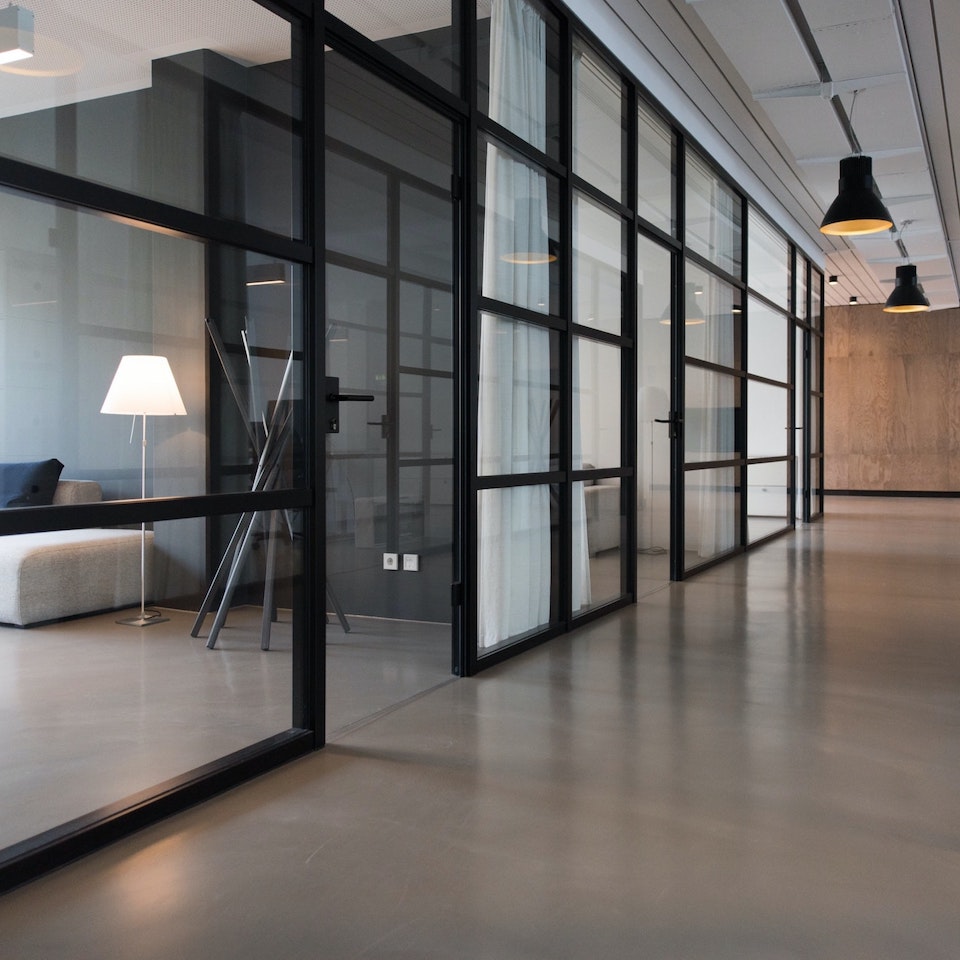 Industrial office with glass walls, black frames and soft furniture in minimal meeting room