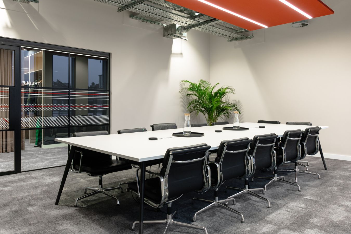 Large collaboration table in modern conference meeting room decorated with plants and big glass windows