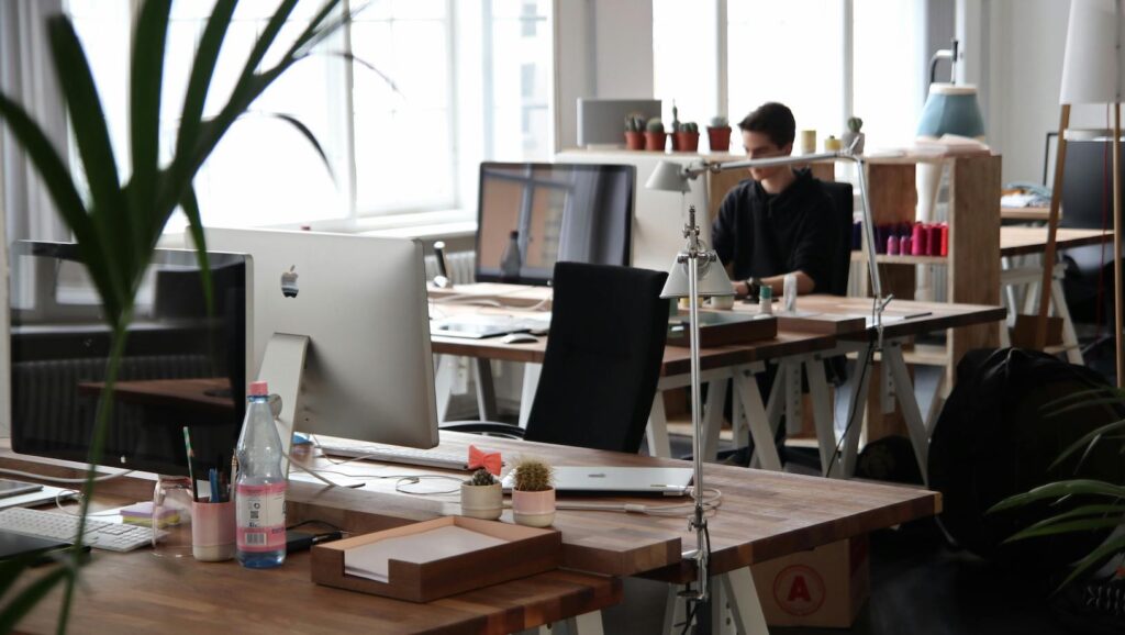 Empty office chair with computers on desk in modern well-lit work environment