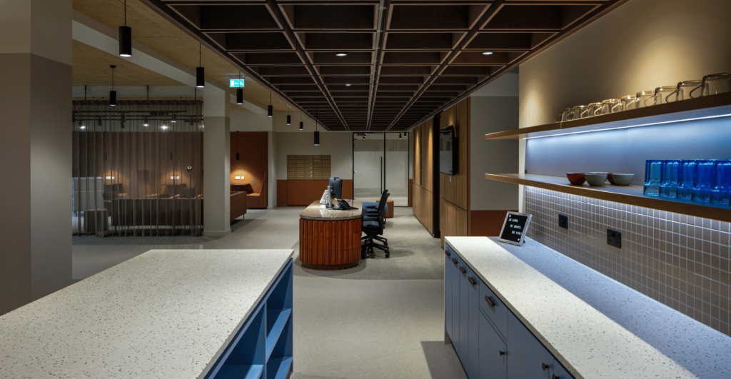 Kitchen and communal area in atmospherically lit office with reception island