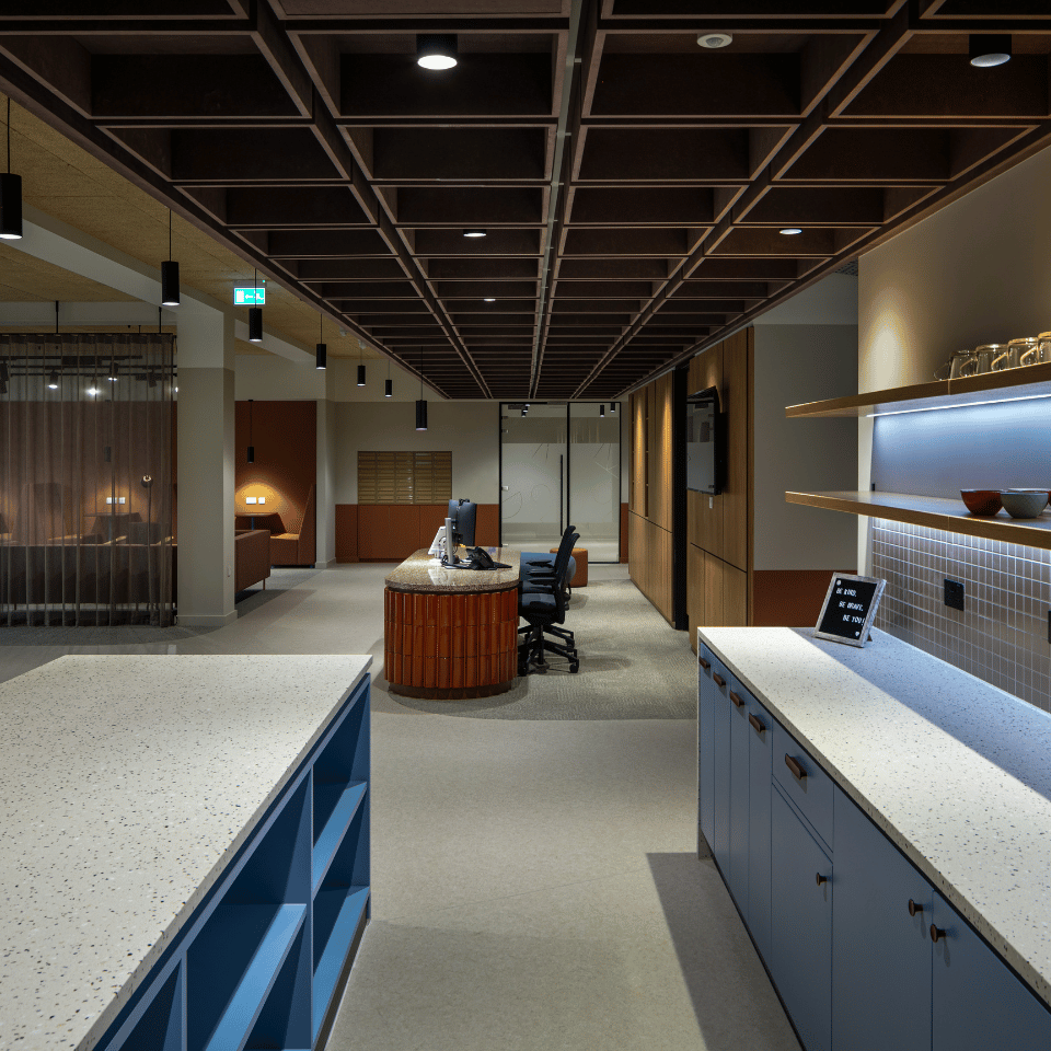 Kitchen and communal area in atmospherically lit office with reception island