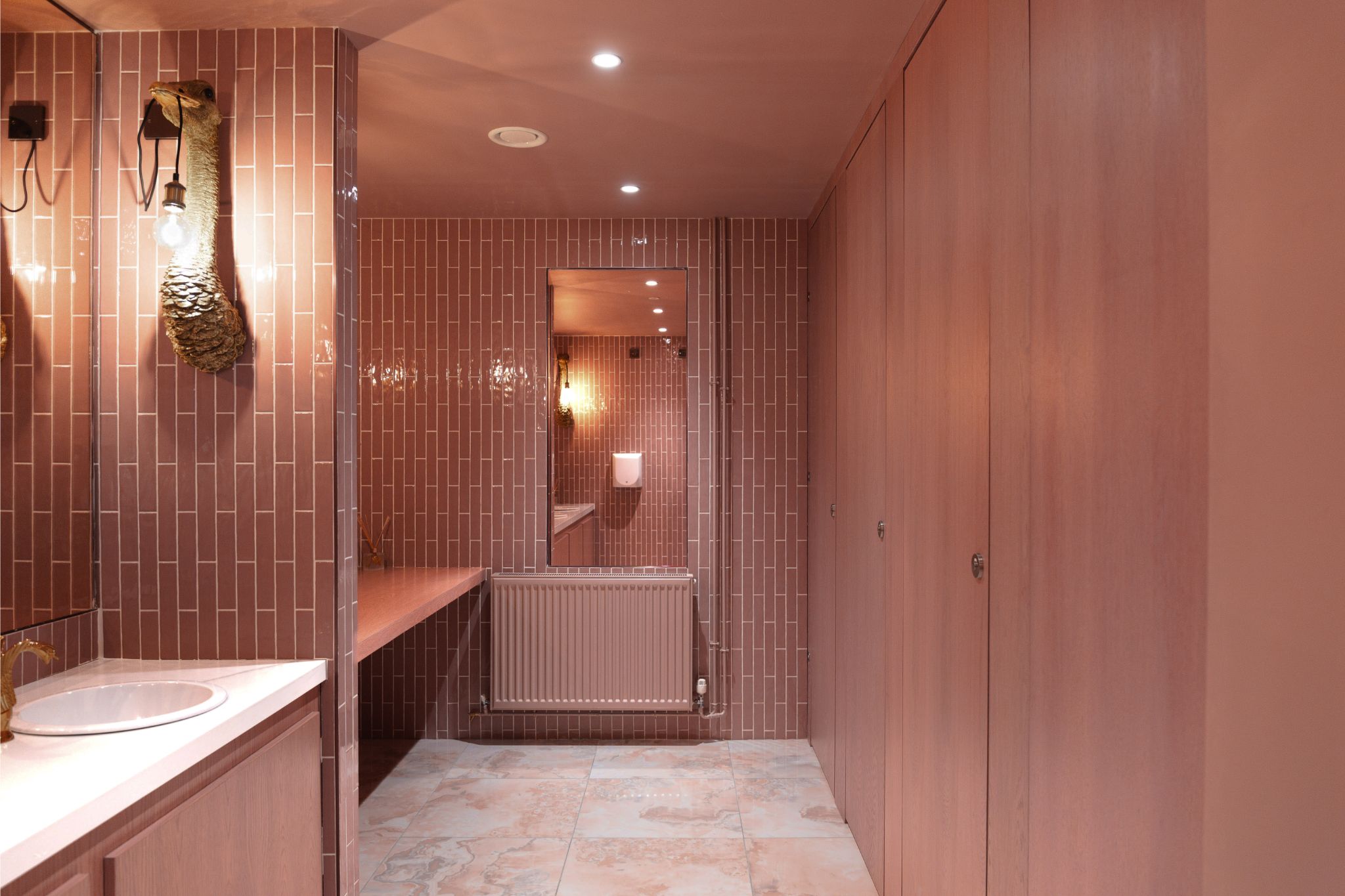 Bright pink themed bathroom with matching tiles and abstract lighting