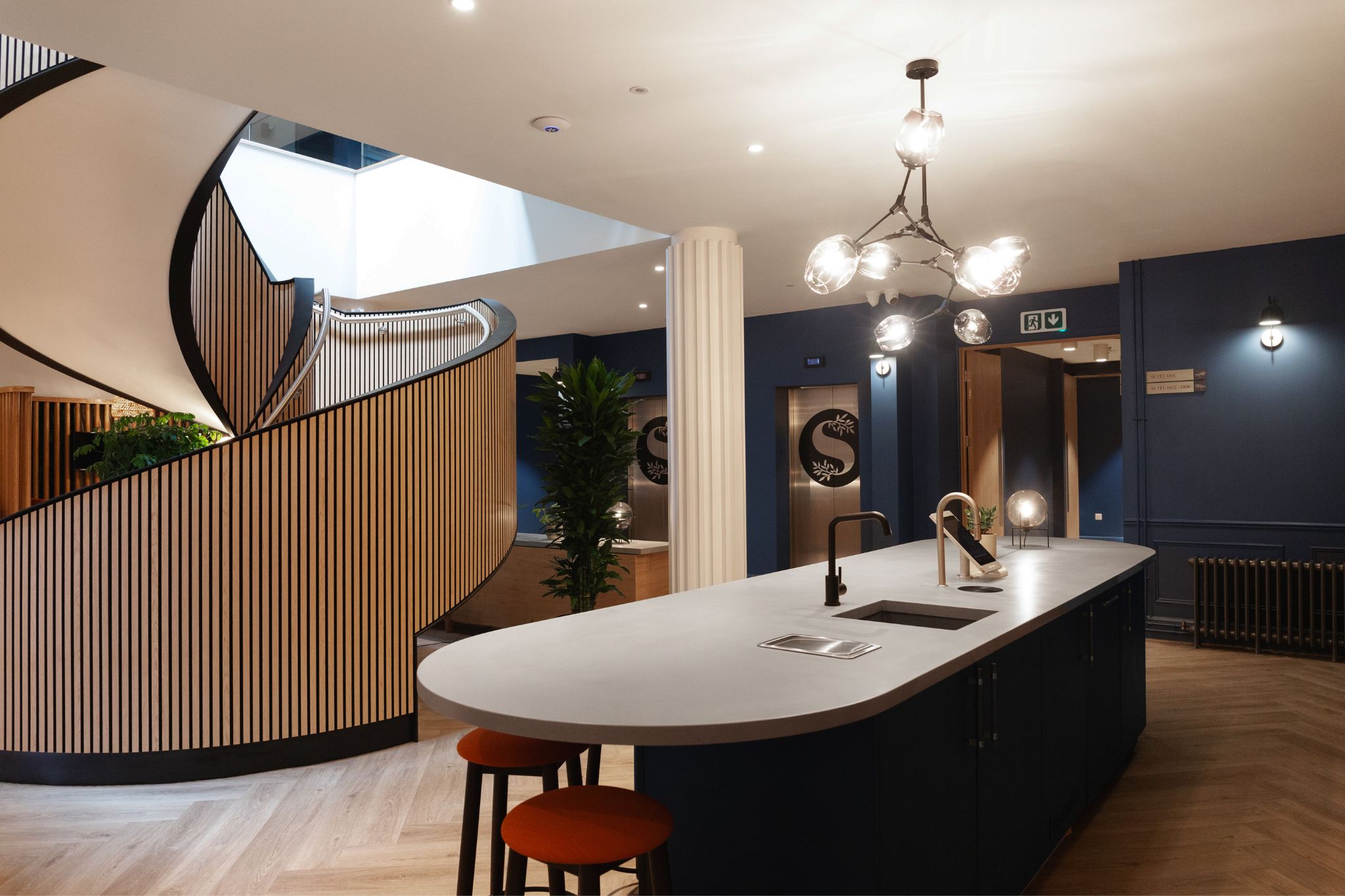 Bespoke staircase in the centre of a common area in a working office with kitchen island